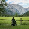 Man on a wheelchair in a mountain meadow