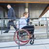 Woman in wheelchair using ramp to enter business