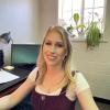 Blonde-haired woman smiling at desk.